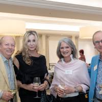 Group of four event guests standing together and posing for photo